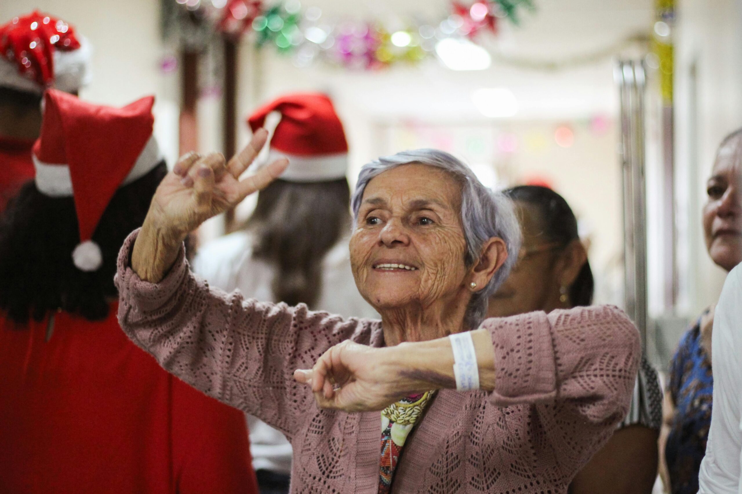 Joyful elderly woman celebrating indoors during a festive Christmas event.