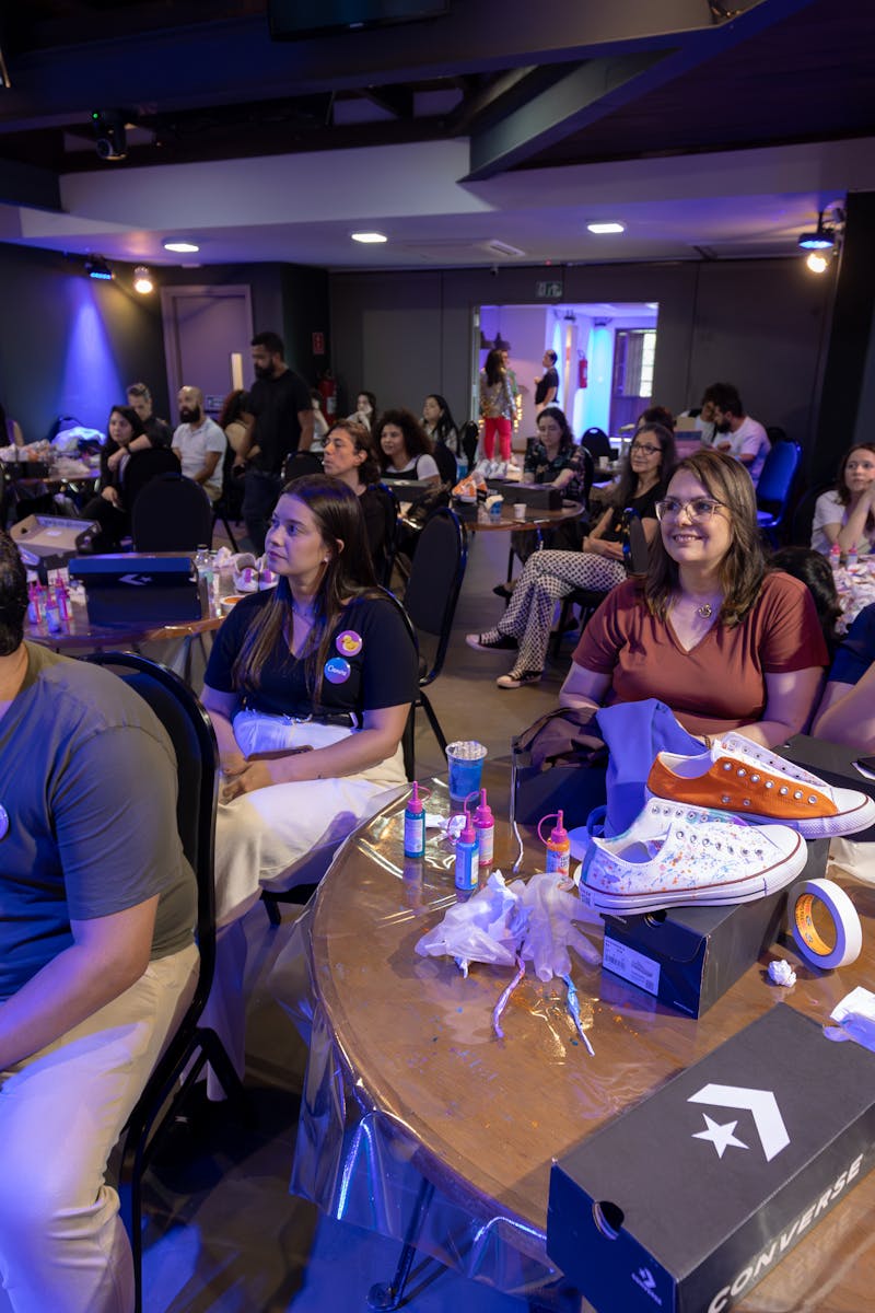 Group of adults attending an indoor workshop featuring Converse sneakers on table.