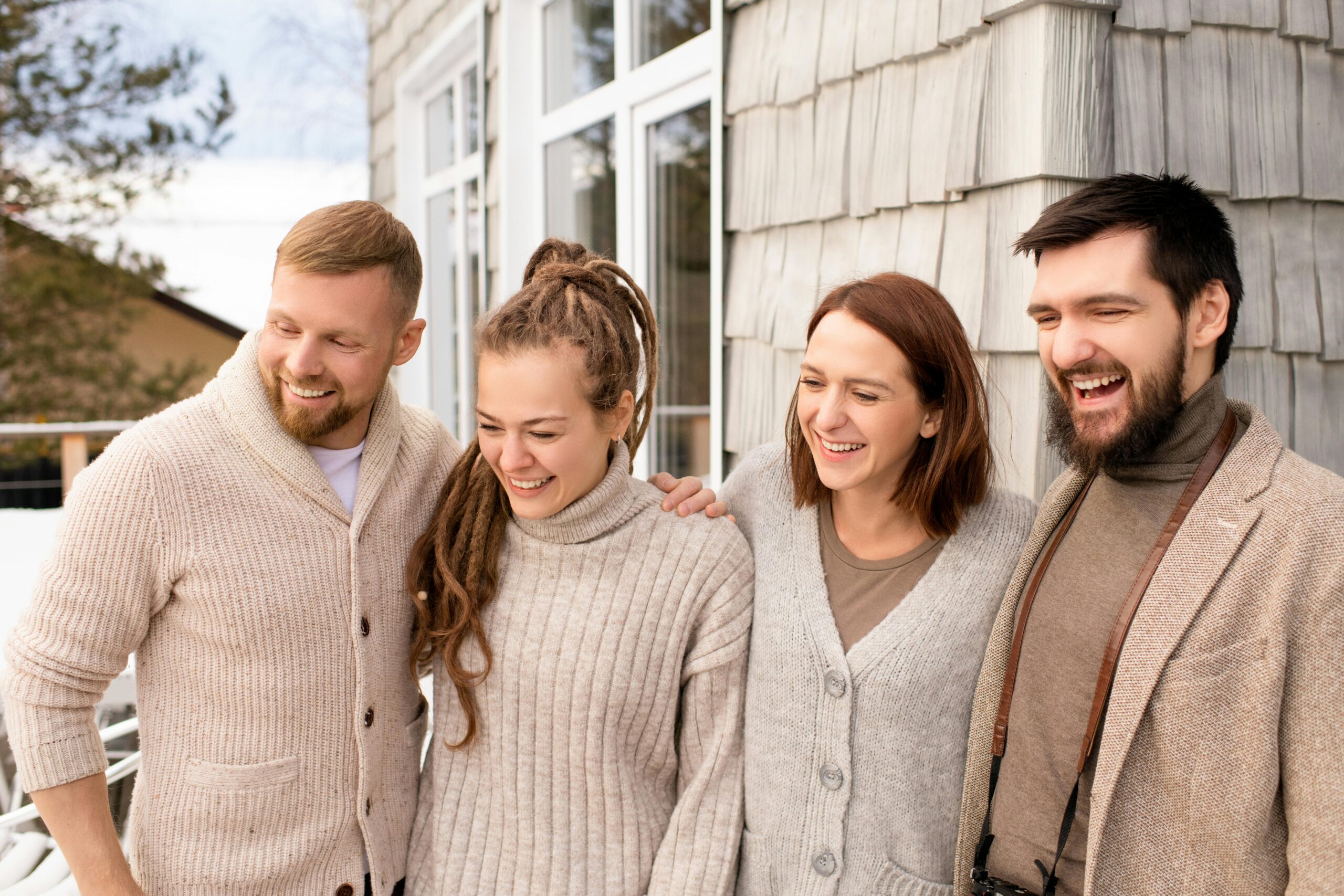 Four friends laughing and bonding outdoors in a cozy winter setting.