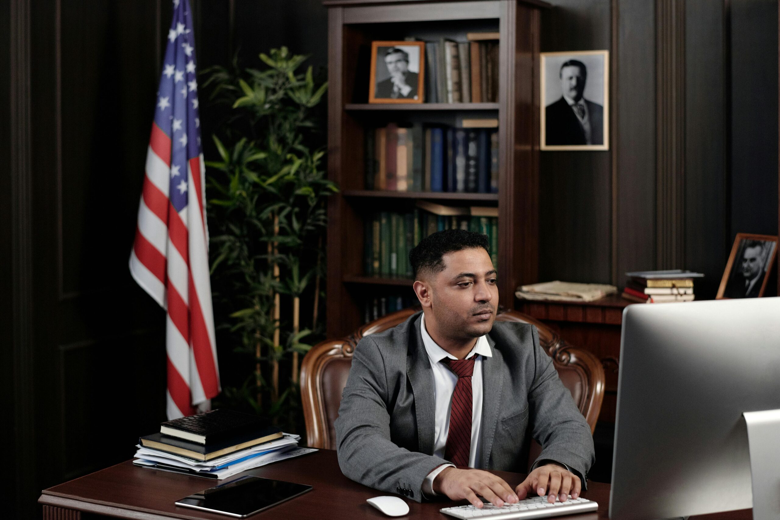 A confident businessman works at his desk with an American flag in his office.