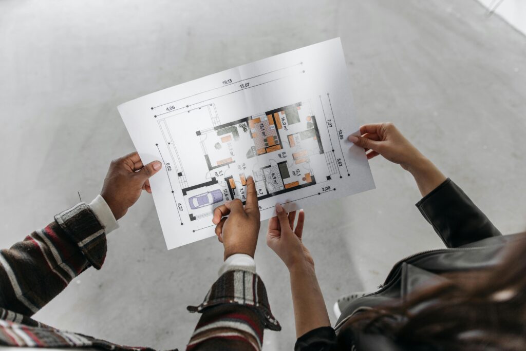 Projetos Two people reviewing architectural plans and measuring a new home design.