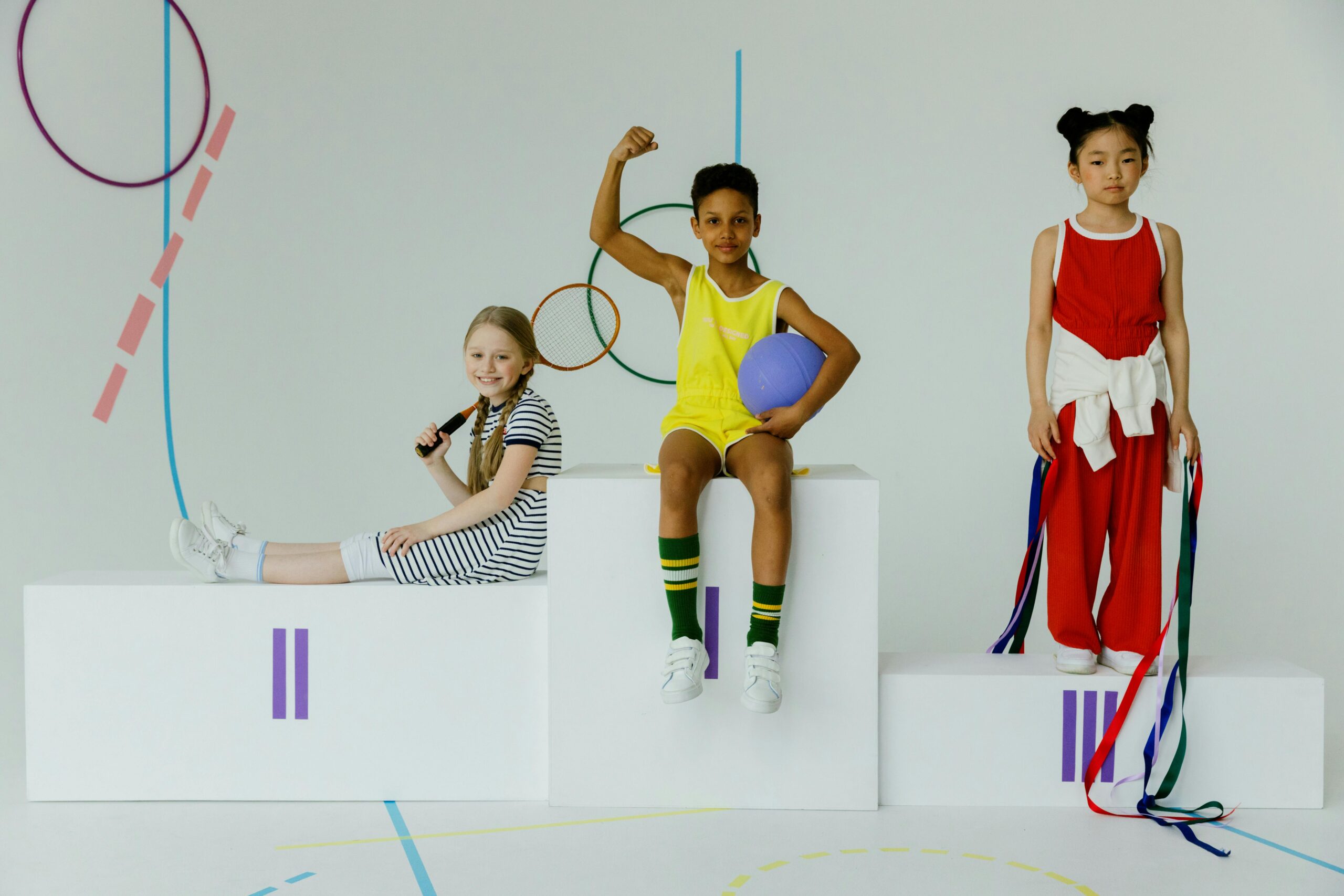 Children celebrating with sports equipment on a podium. Diversity and joy captured indoors.
